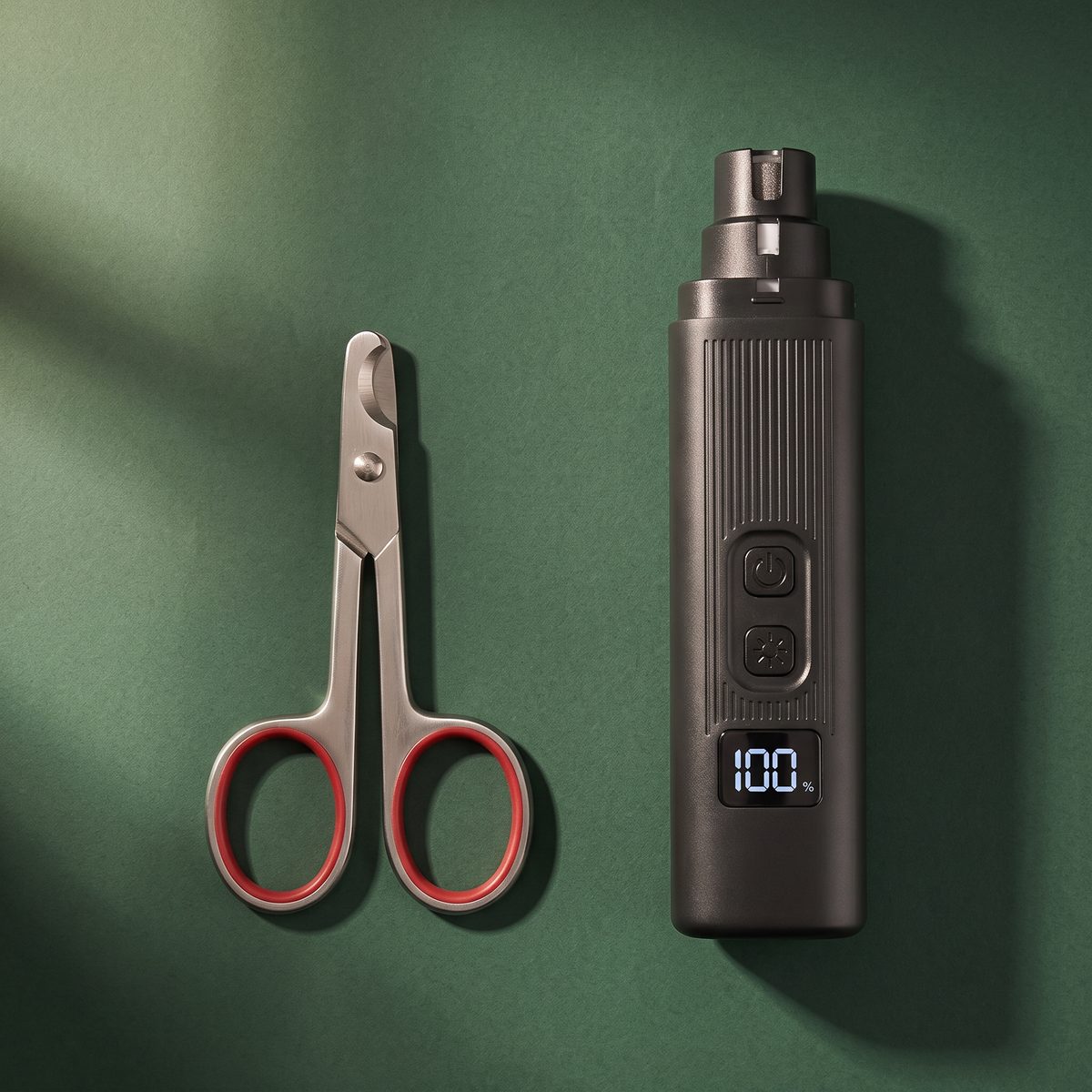 A pair of steel nail clippers beside the grinder, shot from above.